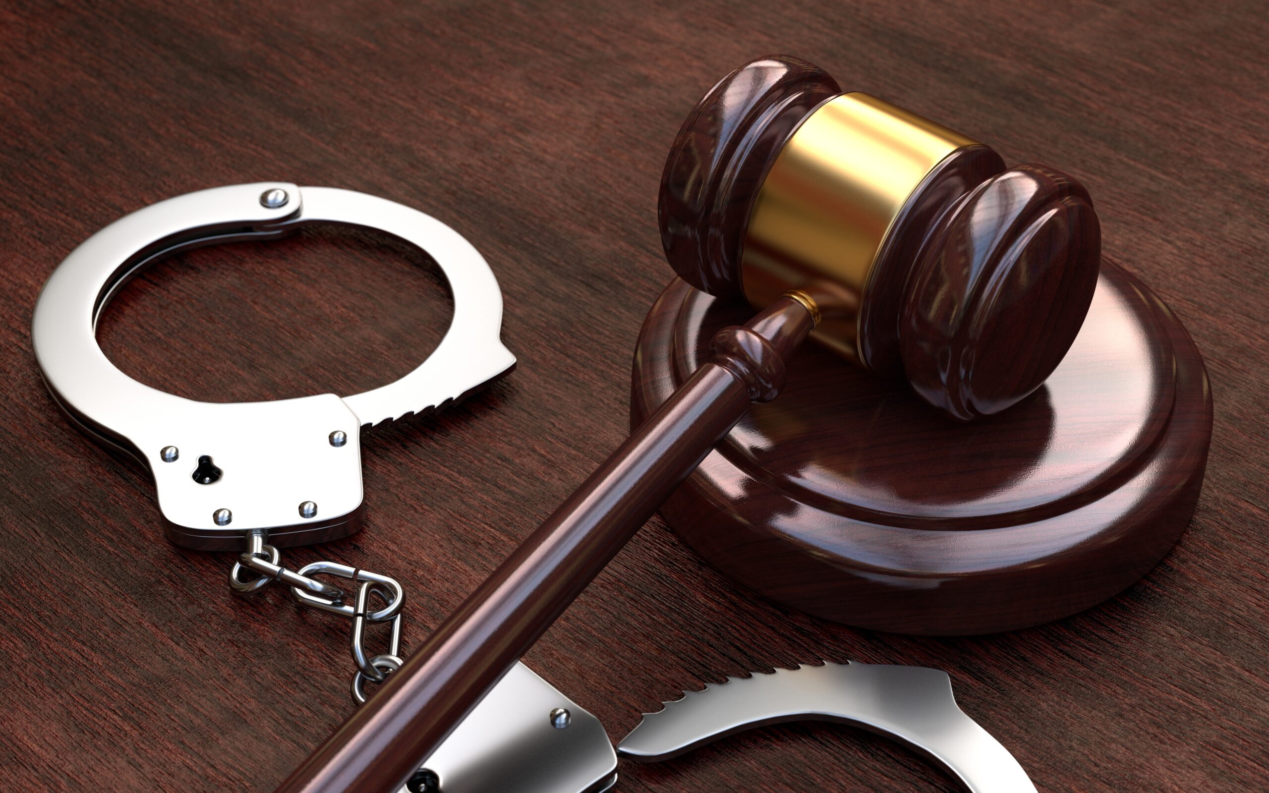 Gavel and handcuffs on wooden brown table background