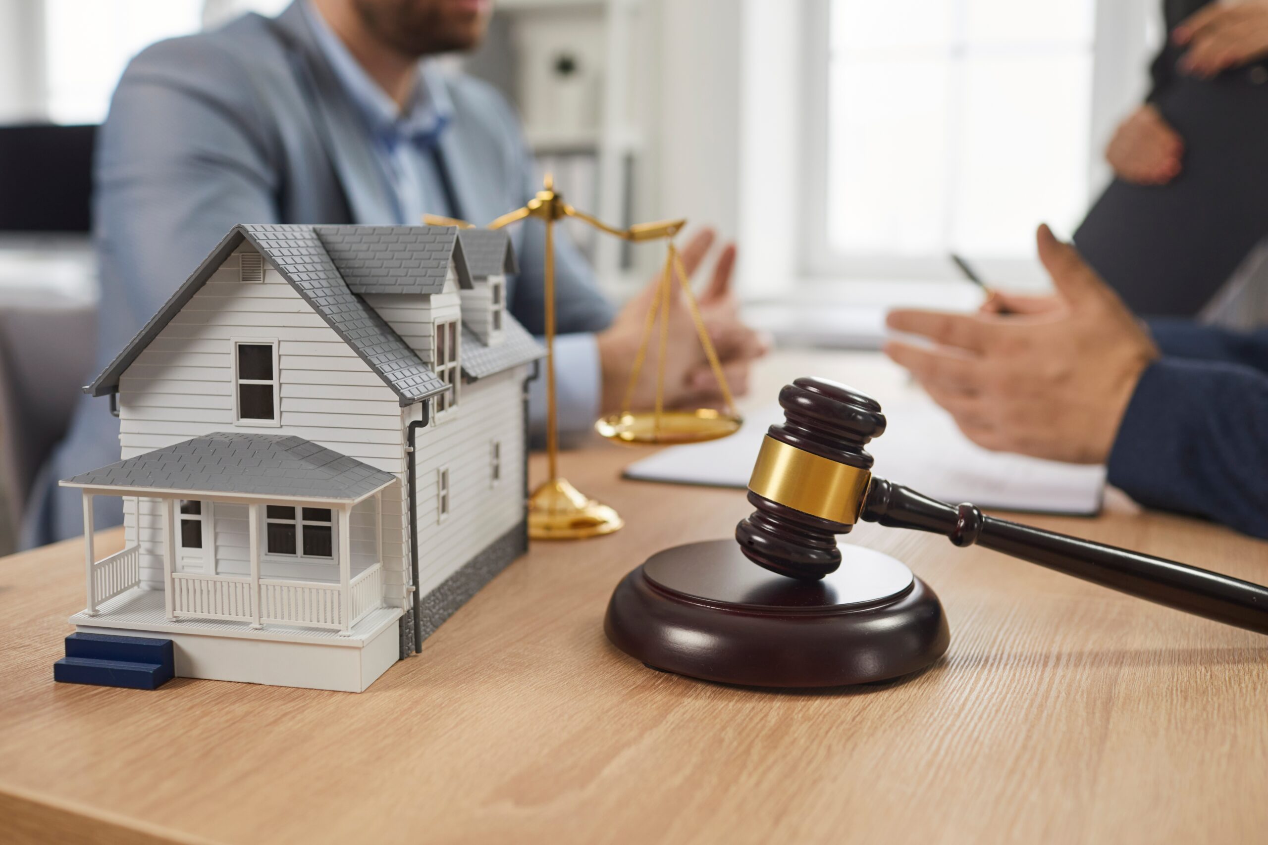 Group of people meeting and talking at office table with gavel and residential house model.